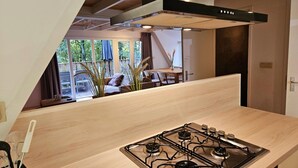 Cozinha moderna com fogão a gás, bancada de madeira e uma grande janela com vista para um deck.