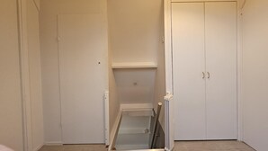 Una stanza con un armadio bianco, uno scaffale piccolo e una porta con maniglia.