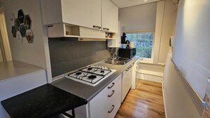 Una cucina moderna con mobili bianchi, un fornello a gas, un lavello e una finestra che offre vista all'esterno.
