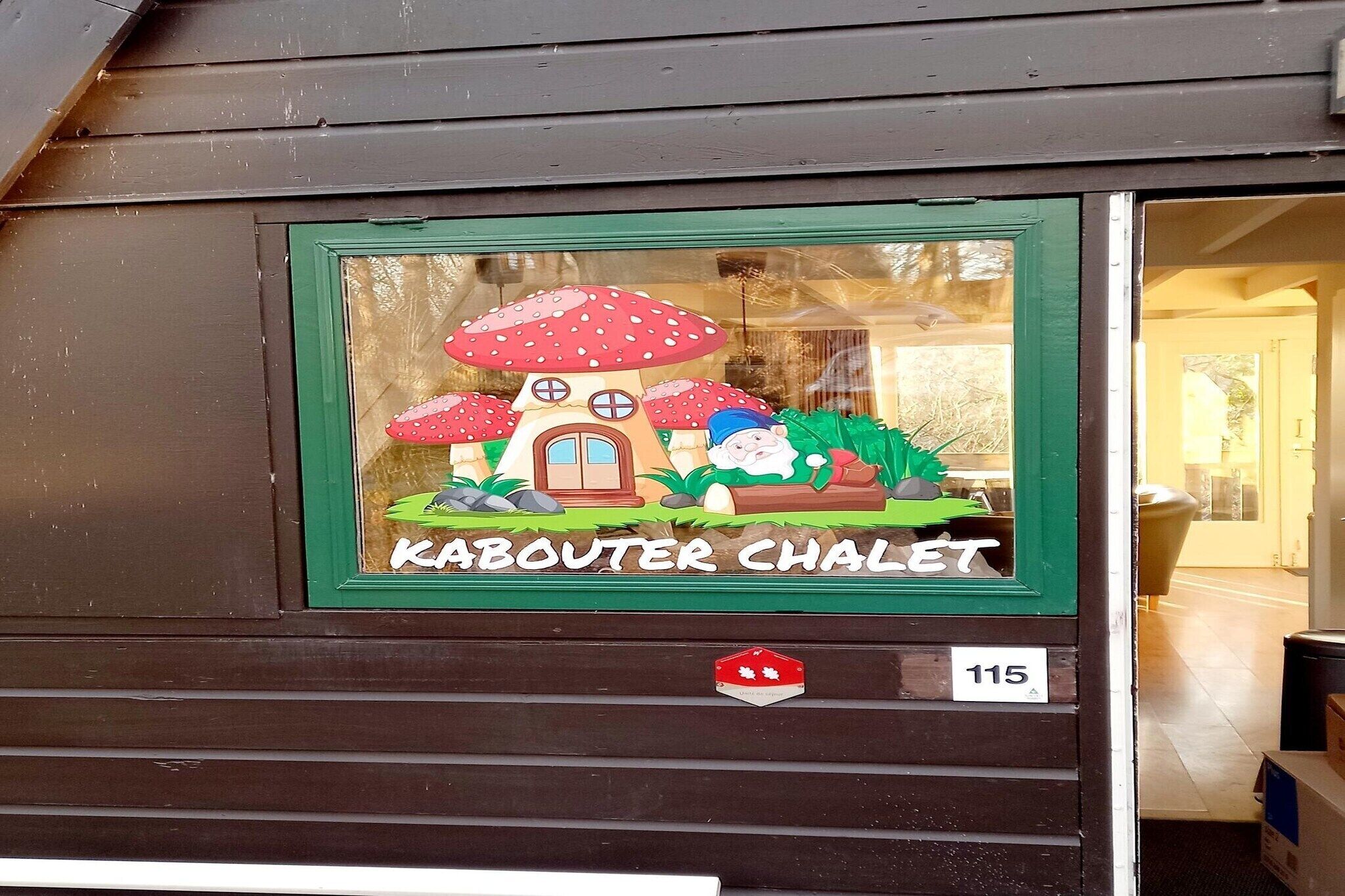 Et vindue med et Kabouter Chalet klistermærke, et rødt ahornblad emblem og nummer 115.
