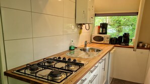 A kitchen with a gas stove, sink, and a window with a view of greenery. - Serene Vacation Chalet in Durbuy (Durbuy)