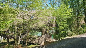 A building with a brick exterior, surrounded by trees and a gravel path. - Serene Vacation Chalet in Durbuy (Durbuy)