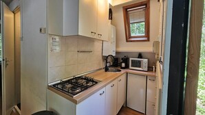 A compact kitchen with a gas stove, a microwave, and a coffee maker.