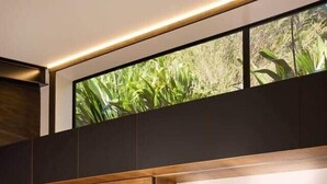 Een moderne keuken met donkere kastjes, een betegelde spatwand en een groot raam met uitzicht op groen.