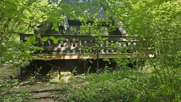 A wooden cabin with a deck, surrounded by dense greenery. - Nature Retreat Close to Durbuy Town (Durbuy)
