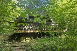 Une cabane en bois dotée d’une terrasse, entourée d’une végétation luxuriante.