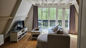 A cozy loft bedroom with a large window, a TV, and a sofa. - Nature Retreat Close to Durbuy Town (Durbuy)