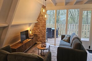 Un salon moderne avec un mur d’accent en pierre, un téléviseur à écran plat et un coin salon confortable comprenant un canapé et des fauteuils.
