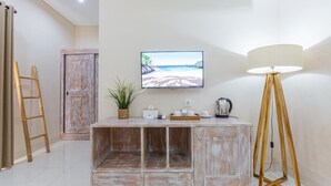 Een kamer met een houten kast, een aan de muur bevestigde televisie en een vloerlamp.