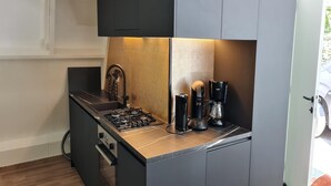 A compact kitchen with a gas stove, coffee maker, and blender on a dark countertop. - Tranquil Countryside Stay in Durbuy (Durbuy)