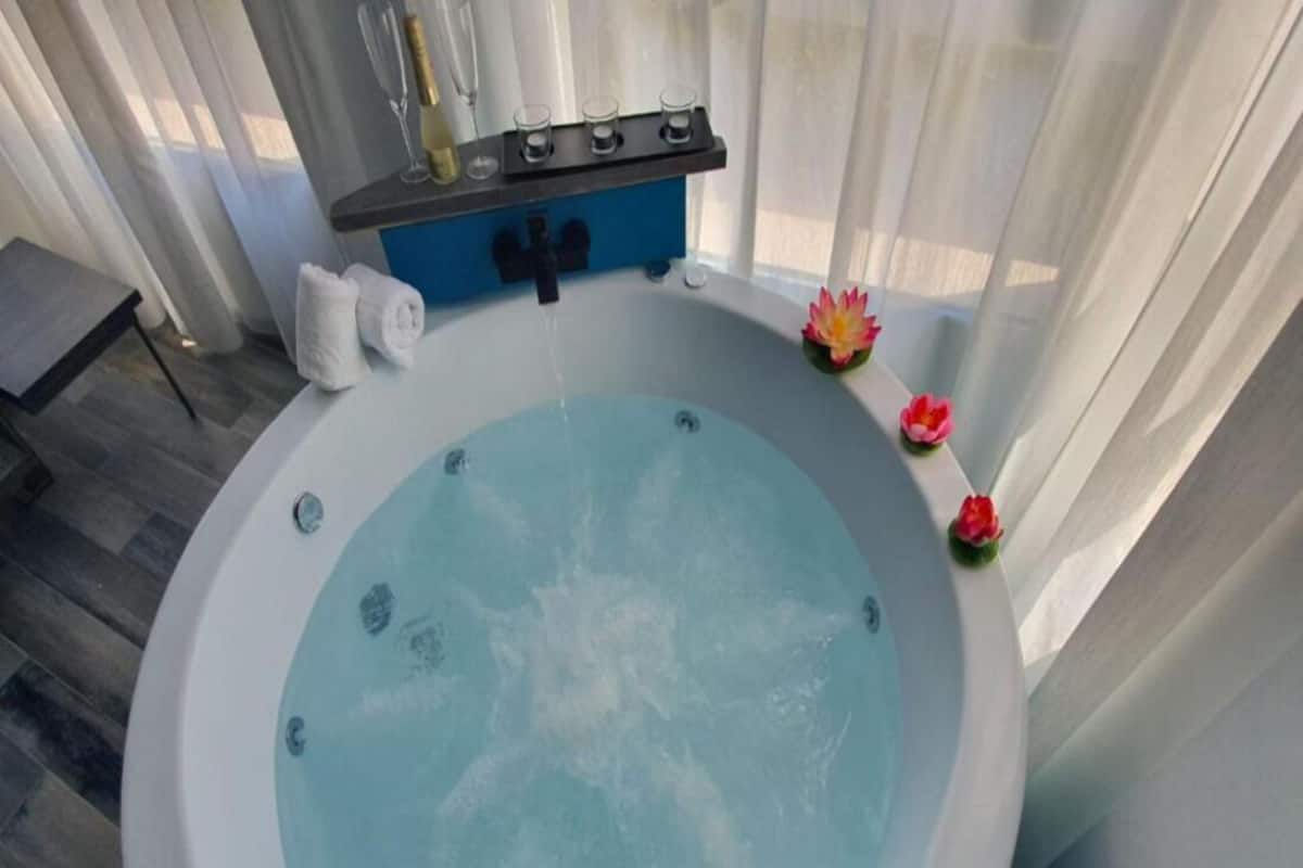 Een bubbelbad met een blauw bedieningspaneel, een handdoekhouder en een lotusbloem decoratie.