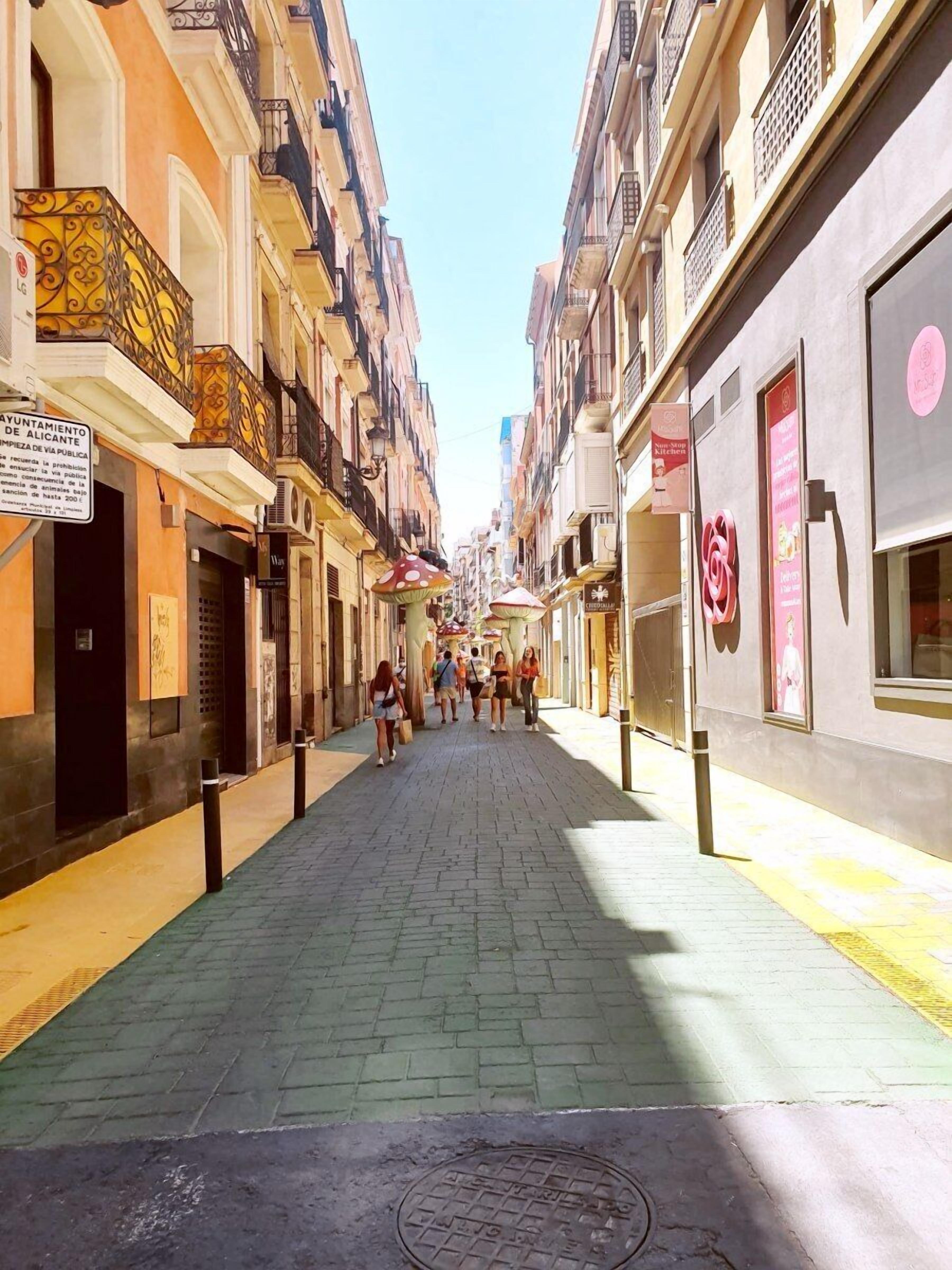 A narrow street lined with multi-story buildings, some with balconies and signage.