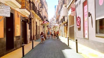 A narrow street lined with multi-story buildings, some with balconies and signage.