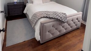 Un dormitorio con una cama grande, una mesita de noche y una lámpara de techo.