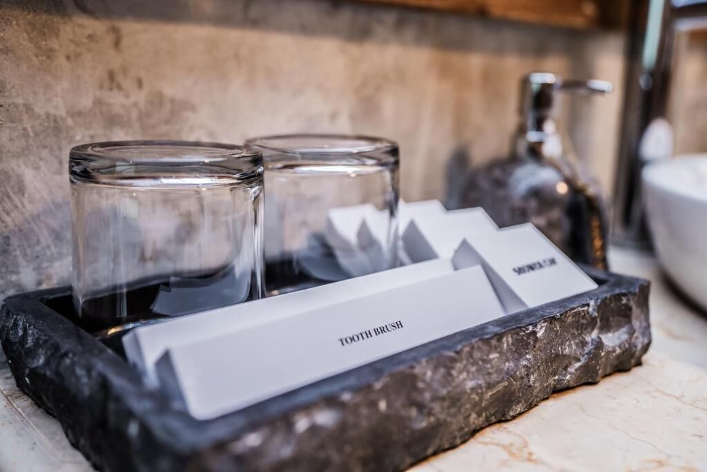 A tray with two glasses and a bottle, with a card labeled "TOOTH BRUSH" on it.