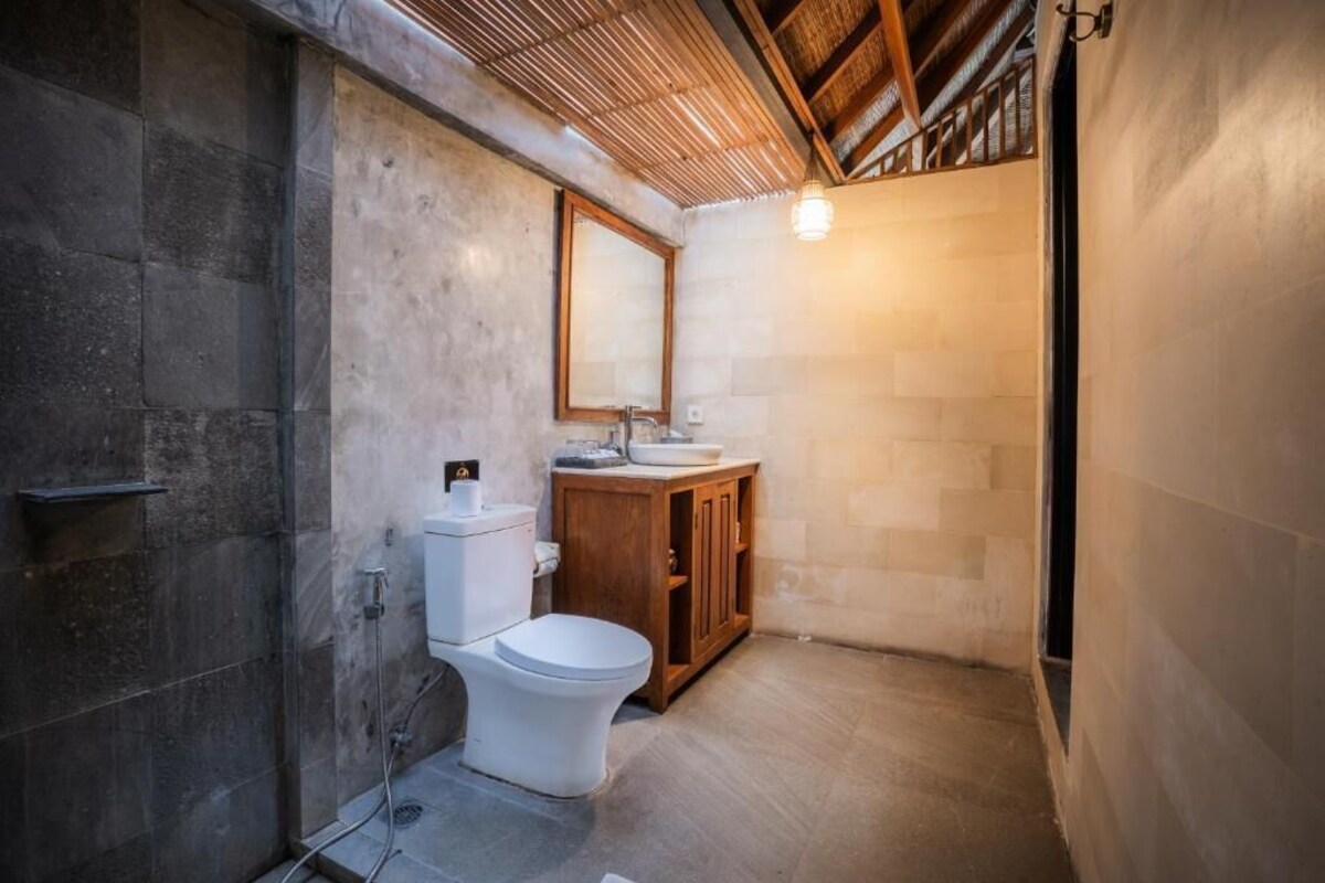 A compact bathroom with a shower, toilet, and wooden cabinet.
