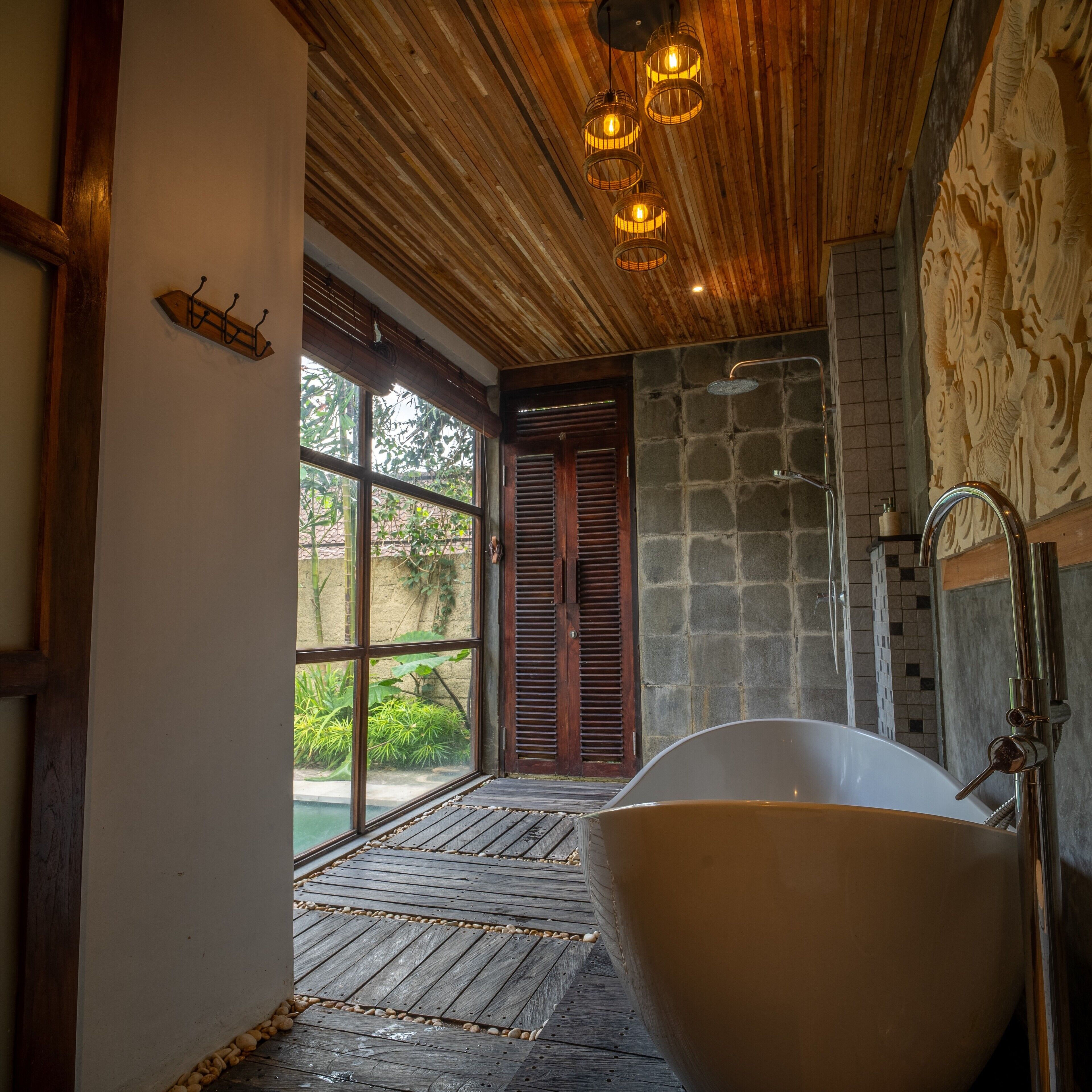 A bathroom with a freestanding bathtub, a stone wall, and a wooden ceiling.