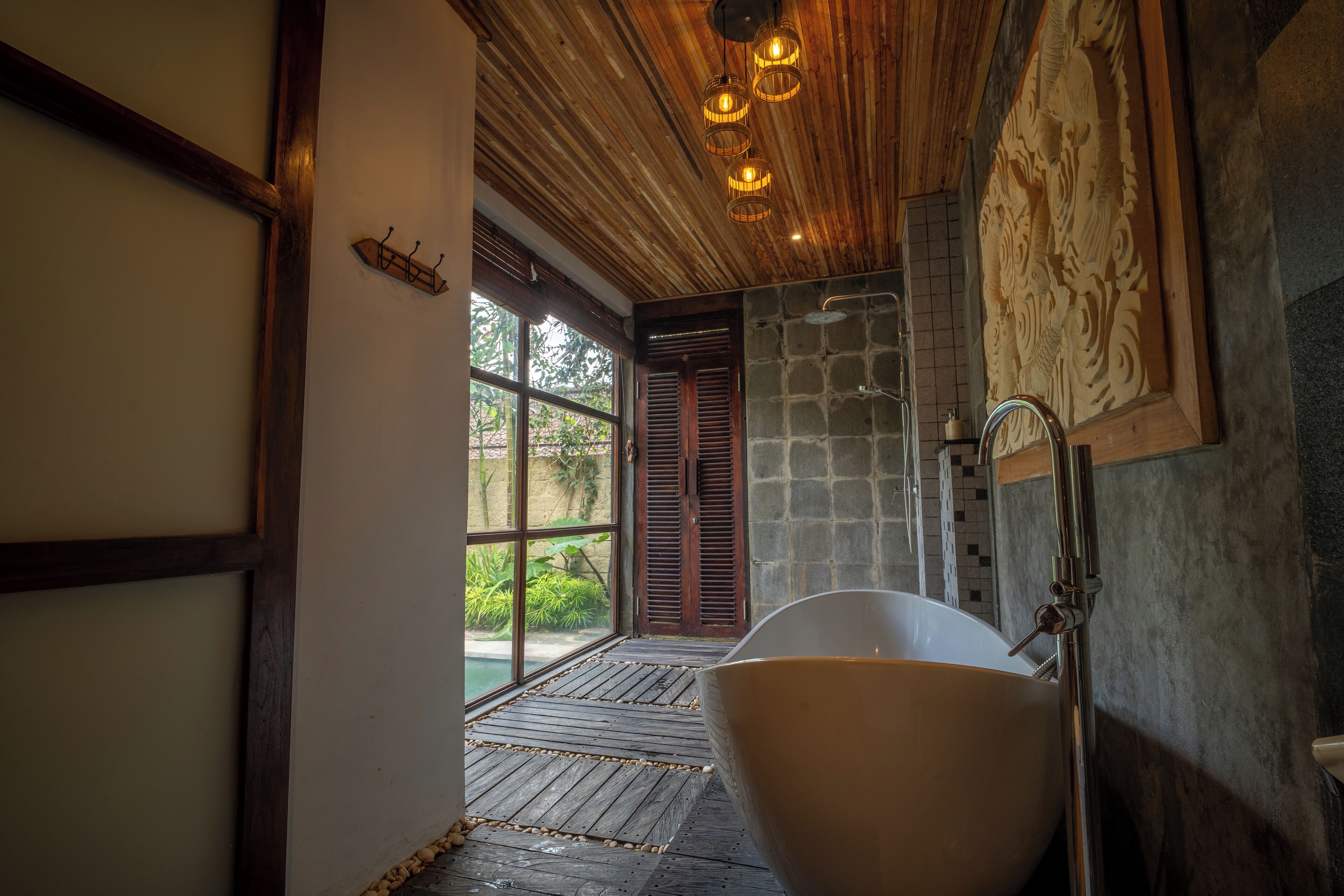 A bathroom with a freestanding bathtub, wooden ceiling, and a stone wall with a carved design.