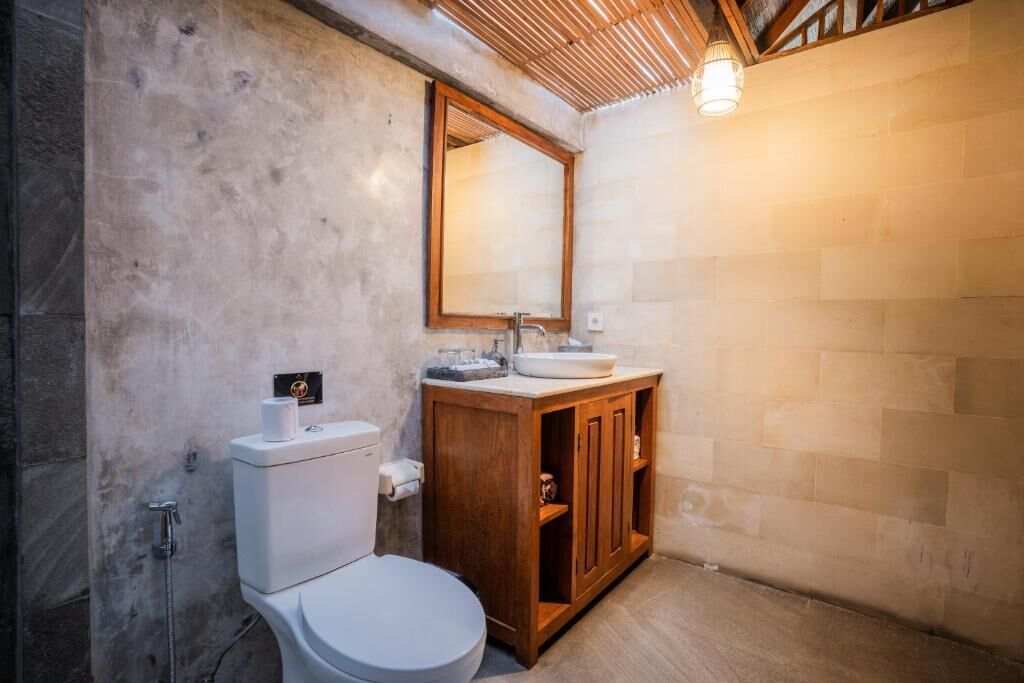 A modern bathroom with a toilet, sink, and wooden cabinet.