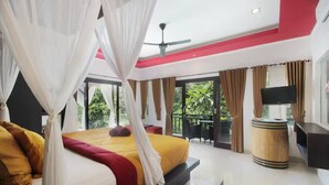 Une chambre d’hôtel équipée d’un lit, d’une télévision, d’un ventilateur de plafond et d’un balcon avec des rideaux.