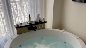 Un baño de spa con diseño de estrella de mar, velas y una botella de champán sobre una mesita.