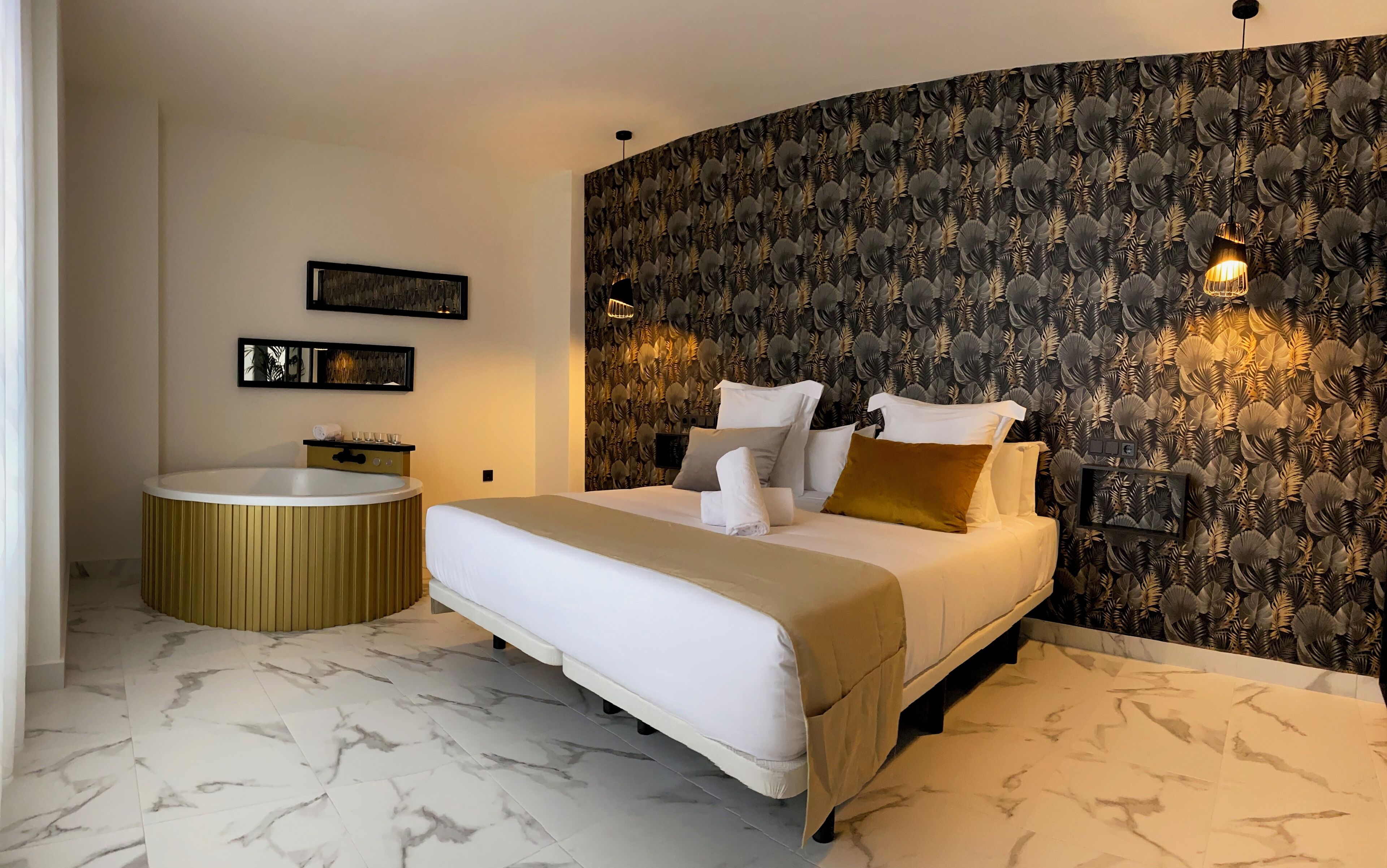 A modern bedroom with a large bed, a round bathtub, and a wall with a leaf pattern.