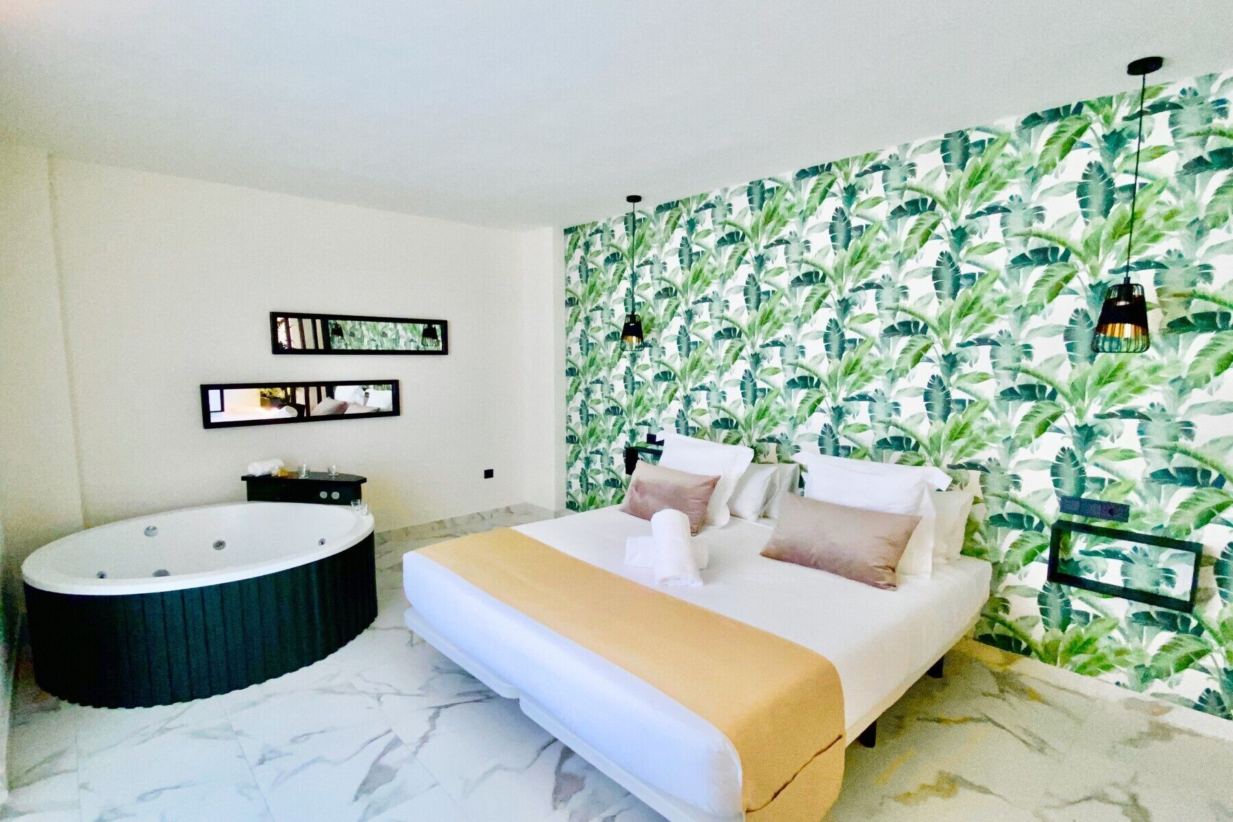 A bedroom with a large bed, a bathtub, and a wall with a leafy pattern.