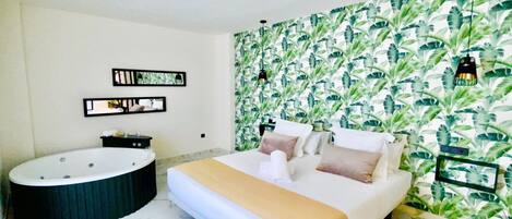 A bedroom with a large bed, a bathtub, and a wall with a leafy pattern.