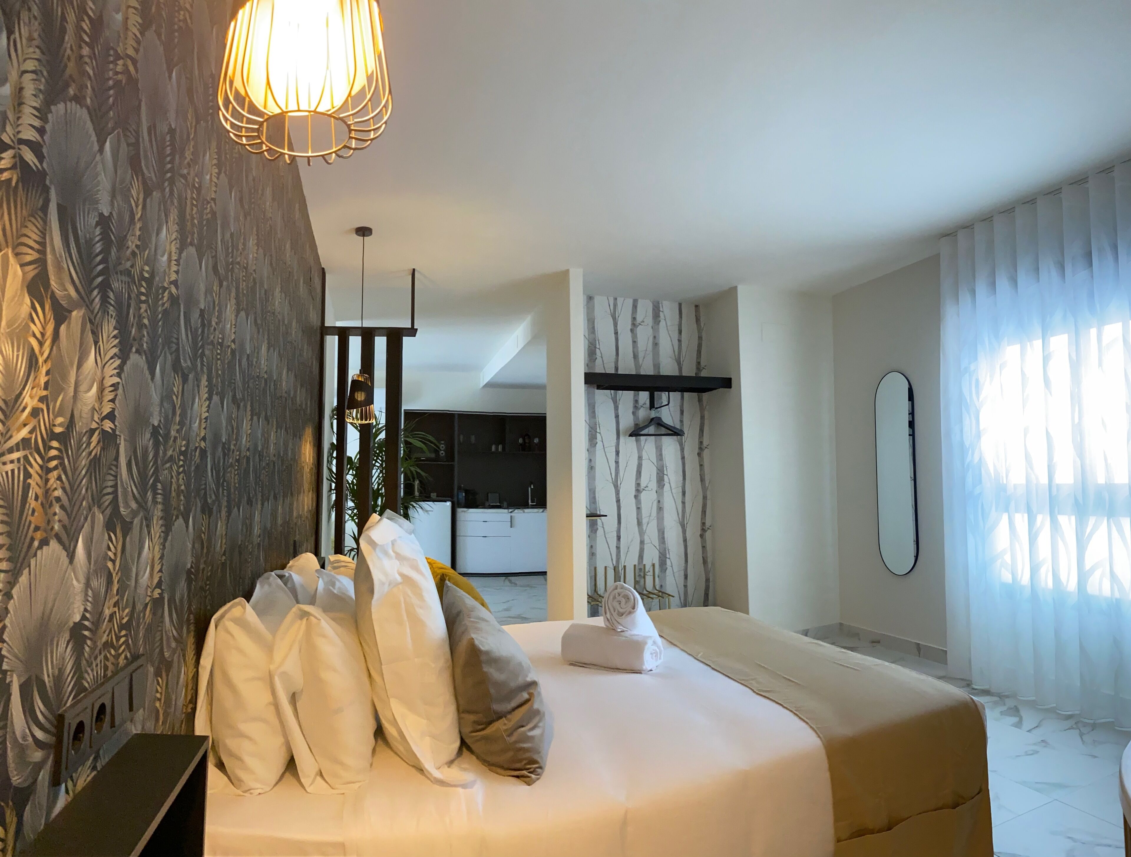 Un dormitorio moderno con una cama grande, una lámpara colgante y un armario con espejo.