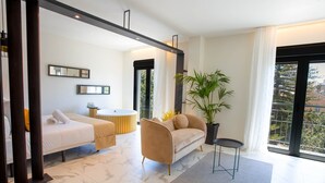 Una sala moderna con un sofá, un sillón, una mesita y una planta grande en maceta.