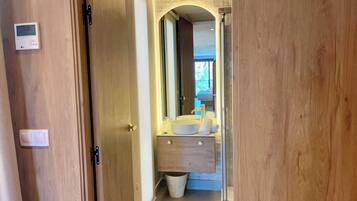 Un baño moderno con un espejo grande, un lavamanos redondo y un perchero para toallas.