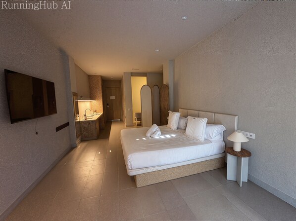 Habitación de hotel con una cama grande, un televisor montado en la pared, una mesita de noche con lámpara y un baño visible a través de una puerta abierta.