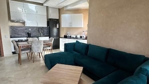 Una sala moderna con un sofá color turquesa, una mesa de centro de madera y un comedor con una mesa y sillas.