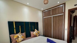Un dormitorio con una cama grande, un armario de madera y una mesita de noche.