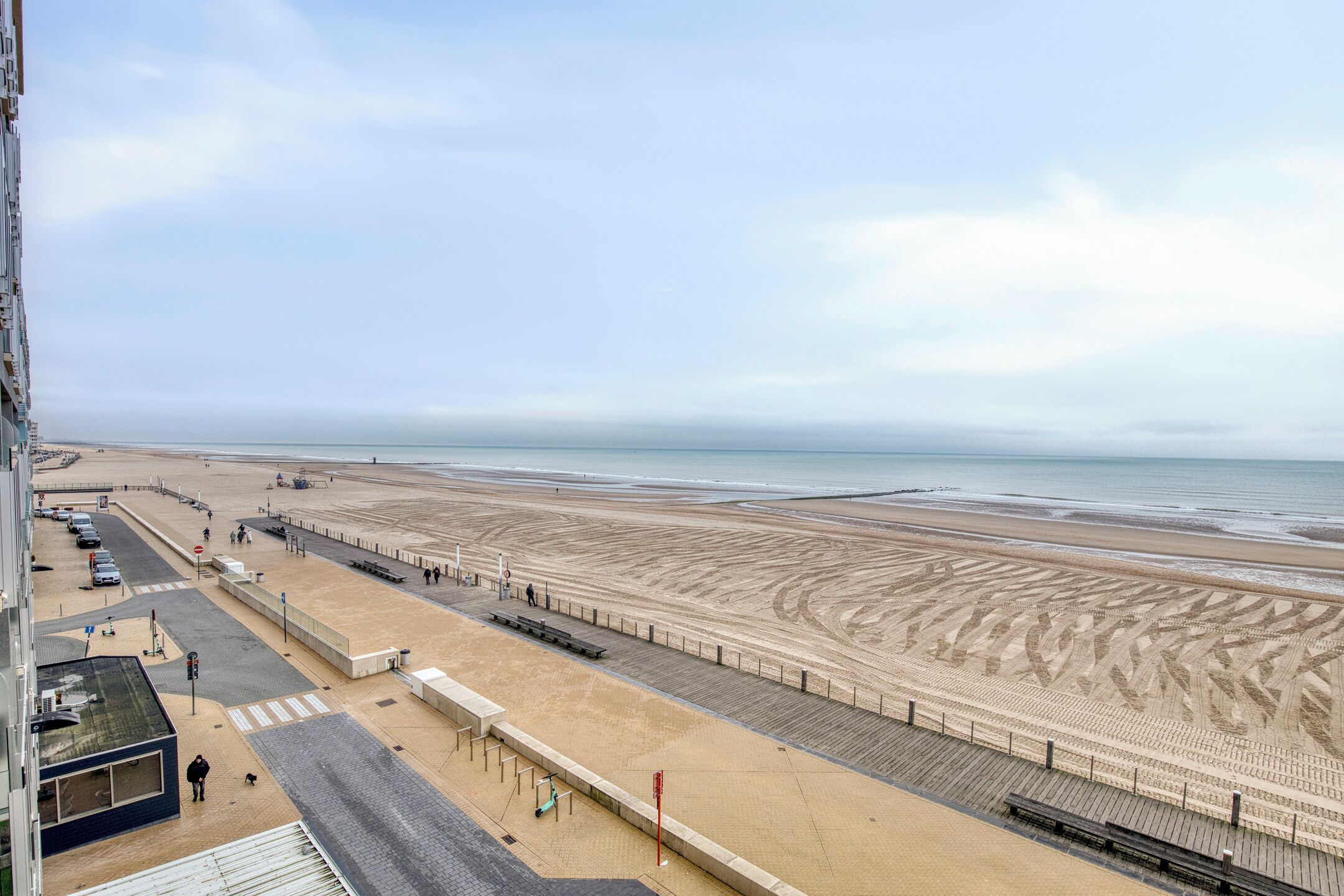 A beach with a boardwalk, benches, and a sandy area.