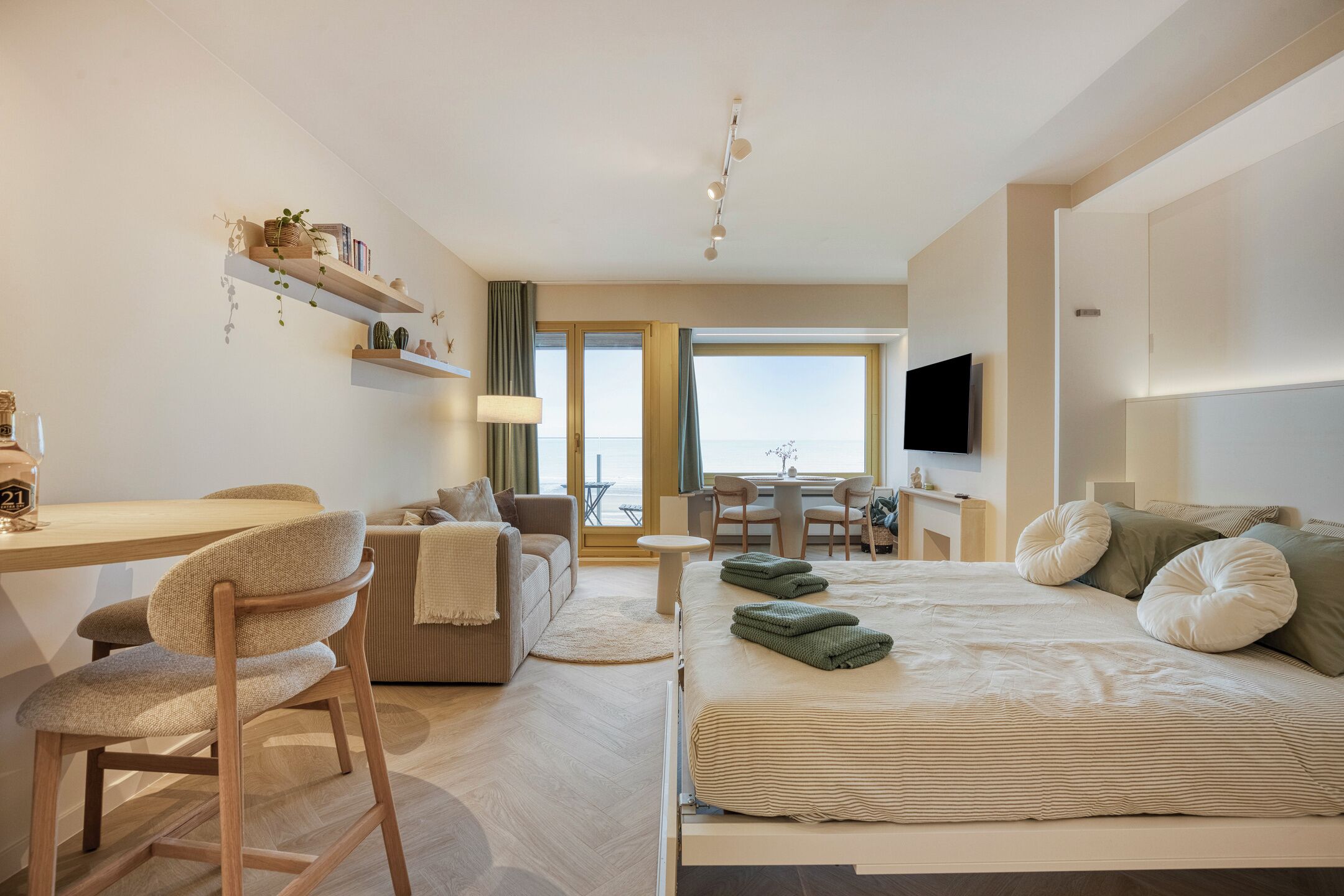 Moderni hotellihuone, jossa on sänky, työpöytä, sohva ja ruokailutila.