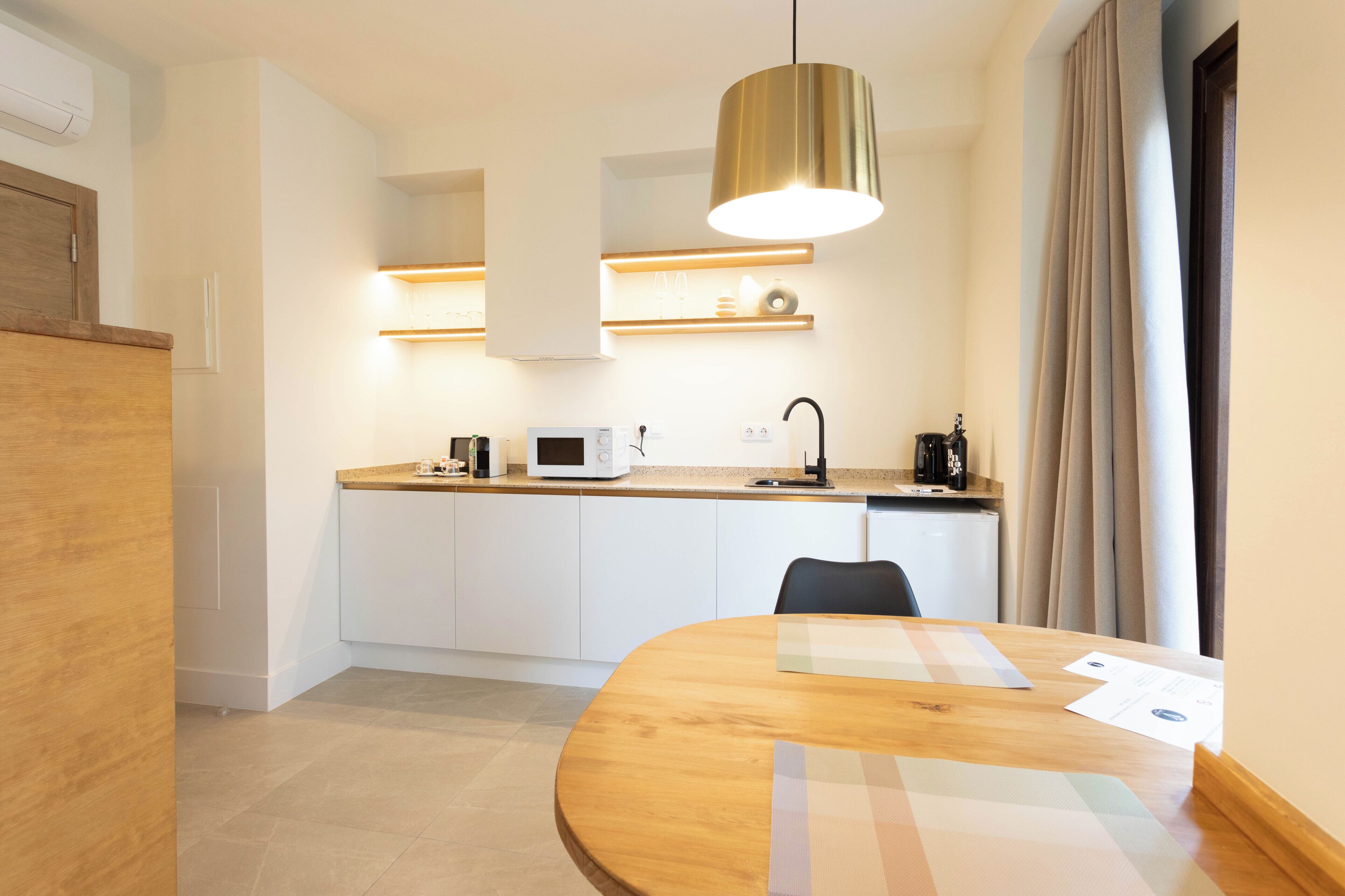 Una cocina moderna con armarios blancos, encimera de madera y una mesa redonda con papeles encima.