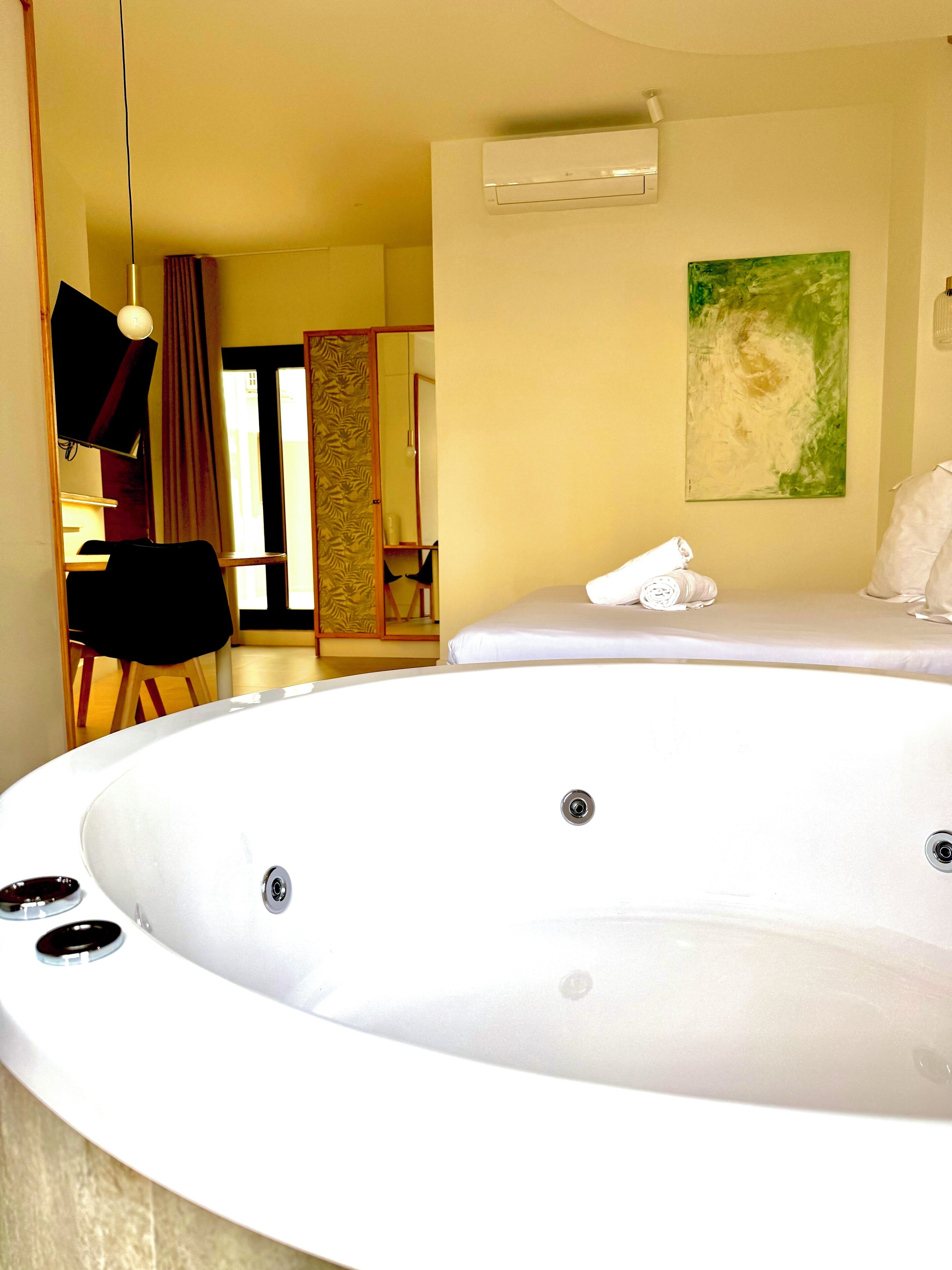 A spa room with a large hot tub, a mirror, and a painting on the wall.