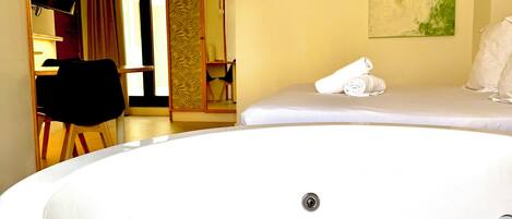 A spa room with a large hot tub, a mirror, and a painting on the wall.