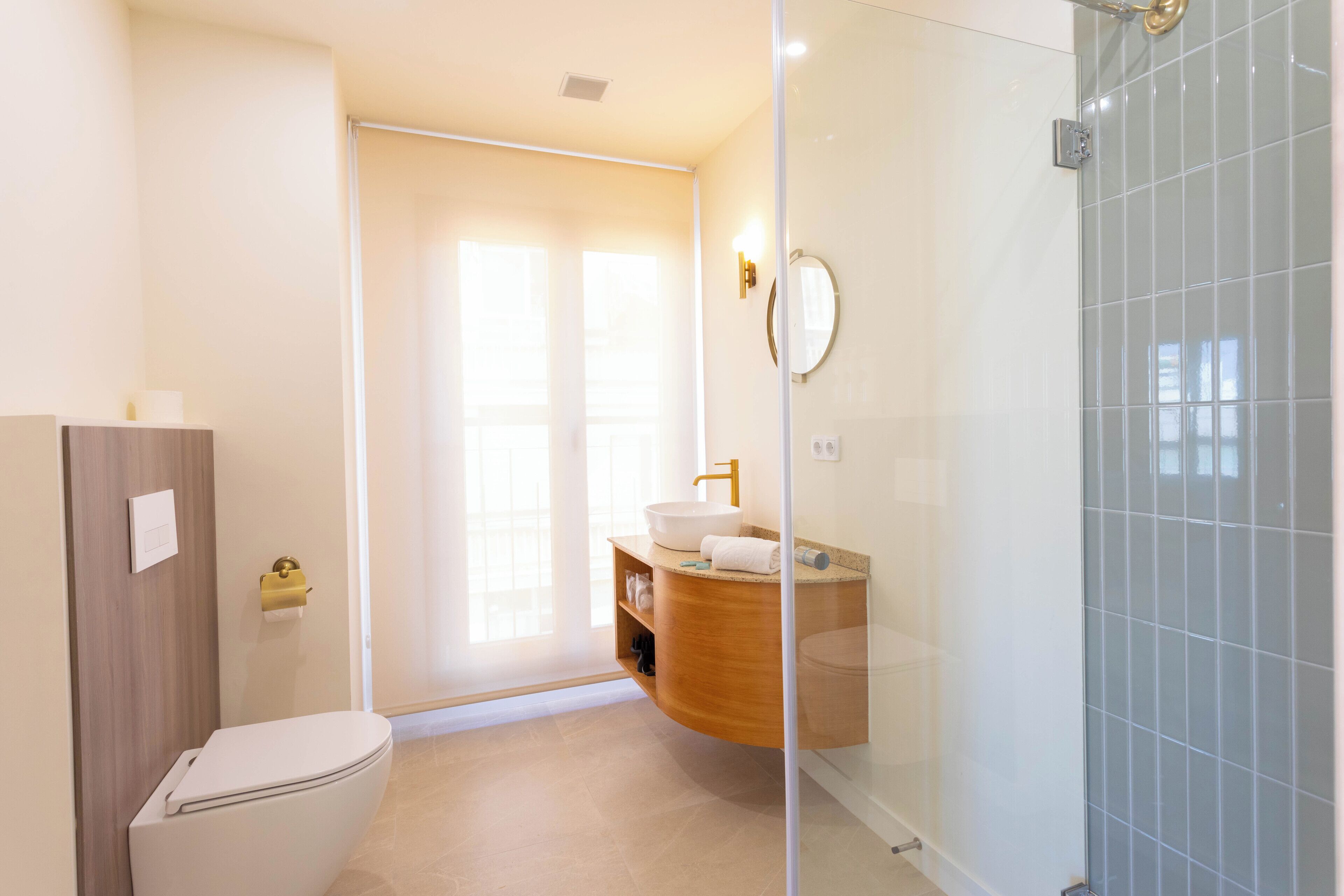 Een moderne badkamer met toilet, wastafel met spiegel en douche.