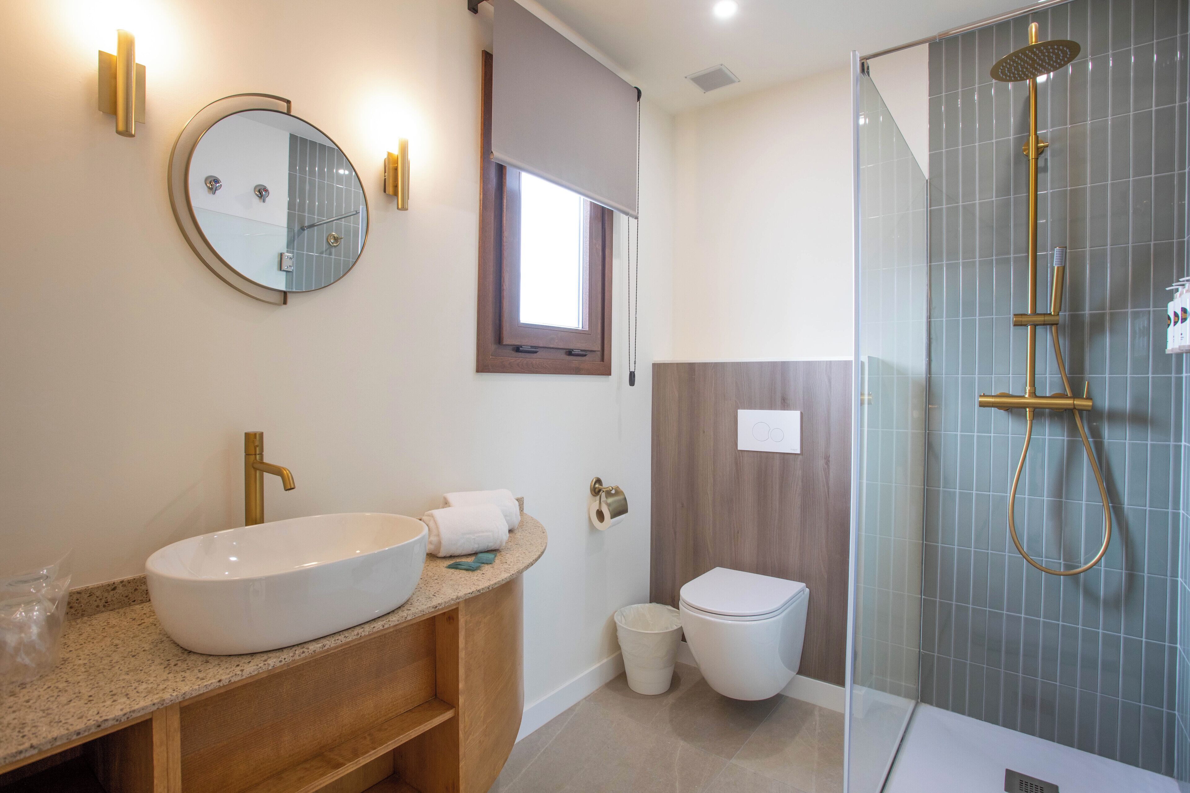 Een moderne badkamer met een vrijstaand bad, een ronde spiegel en een toilet.