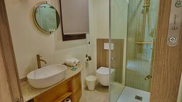 A modern bathroom with a freestanding sink, toilet, and glass-enclosed shower.