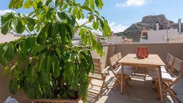 Una terraza con una mesa y sillas de madera, rodeada de plantas verdes.