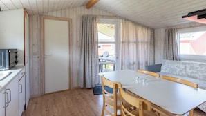 A compact kitchen with a microwave, a sink, and a dining area with a table and chairs. - Rømø familiecamping (Rømø)