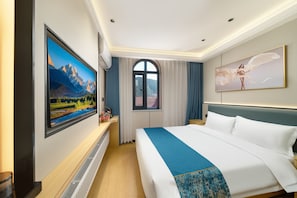Une chambre d’hôtel avec un grand lit, un téléviseur fixé au mur, une fenêtre avec des rideaux et un tableau au-dessus du lit.