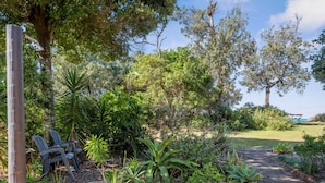 A garden with a paved path, chairs, and various plants. - Shell Cove by Charlesworth (Korora)