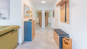 A hallway with a blue cabinet, a wooden bench, and a wooden door. - Sund Huus Altefähr - Urlaub im Süden der Insel (Altefähr)