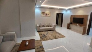 A modern living room with a sofa, coffee table, and a flat-screen TV mounted on the wall. - Palette Luxury Doolv Serviced Apartments Tabuk (Tabuk)