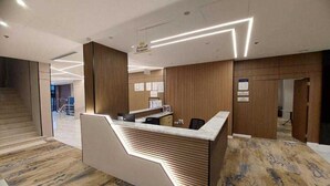 A reception area with a modern reception desk, wooden paneling, and a carpeted floor. - Palette Luxury Doolv Serviced Apartments Tabuk (Tabuk)