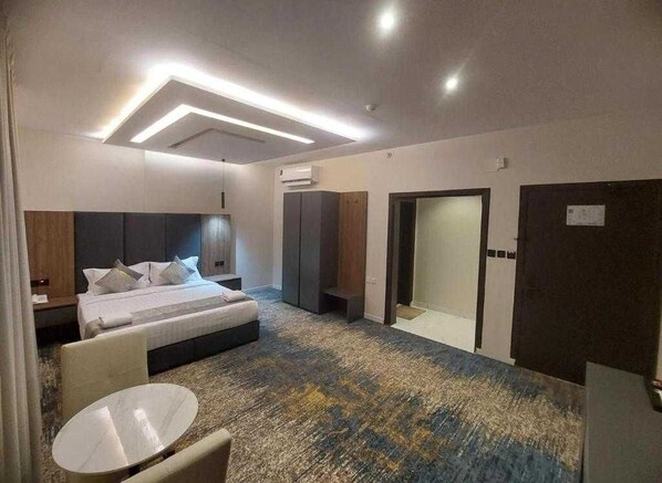 A modern hotel room with a large bed, a round table, and a walk-in closet. - Palette Luxury Doolv Serviced Apartments Tabuk (Tabuk)
